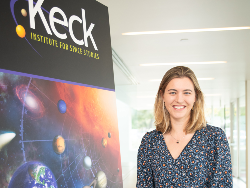 Harriet Brettle in front of a Keck Institute for Space Studies poster