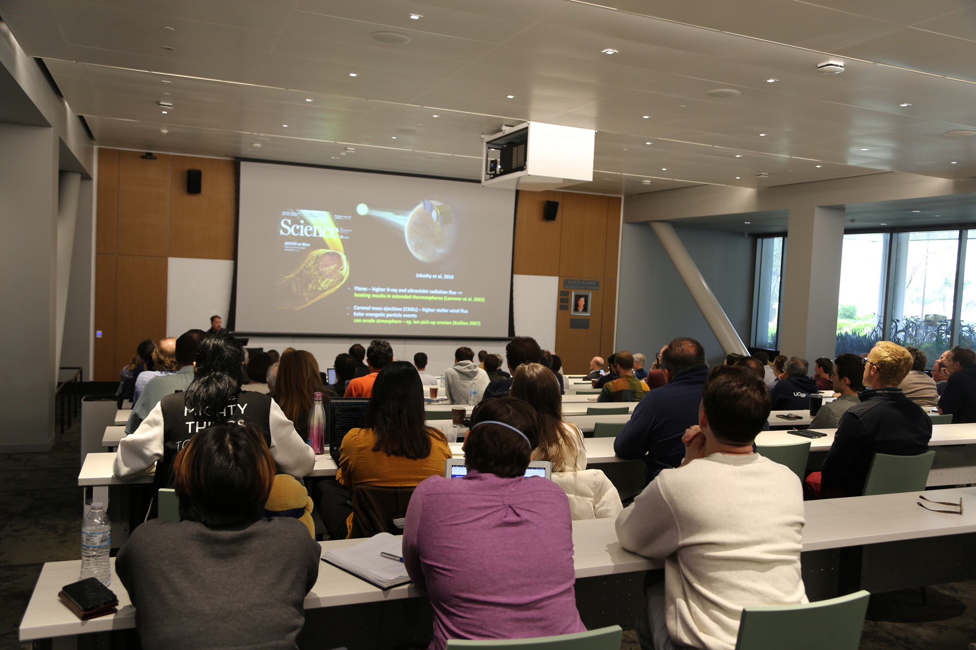 filled lecture hall with a presenter at the front